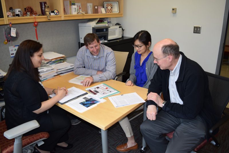 Several faculty members and a graduate student sit around a table as they discuss research.
